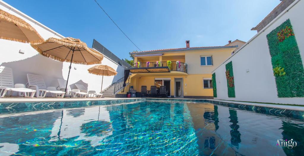 a swimming pool with an umbrella and a house at Villa UpTown in Mostar