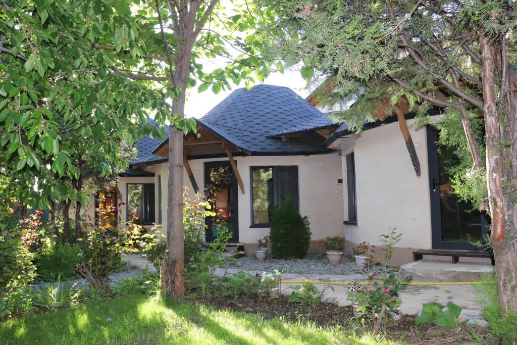 a small white house with a blue roof at Happy Nomads - Modern Yurt Cottages & Breakfast in Karakol