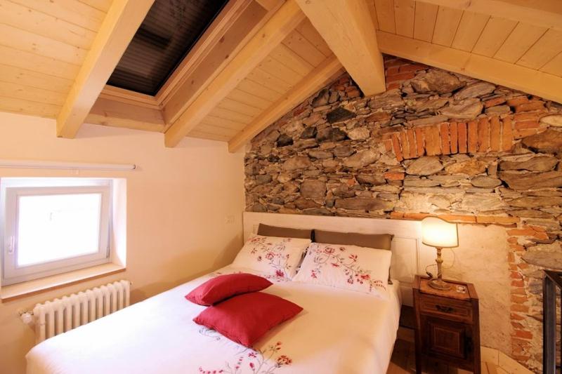 a bedroom with a bed and a stone wall at Guest House Al Castello in Gravedona