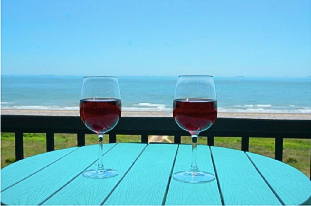 two glasses of wine sitting on a table near the ocean at Beachfront 8th floor Studio - Stunning View in Galveston