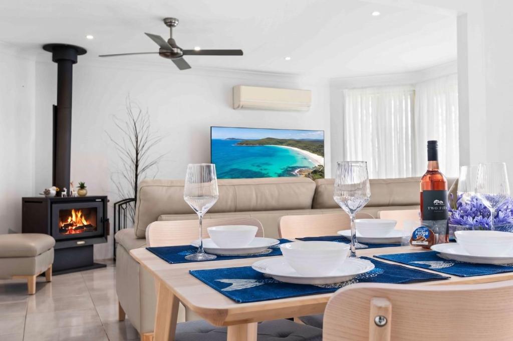 a living room with a table with wine glasses and a couch at Casa LuCe by Experience Jervis Bay in Erowal Bay