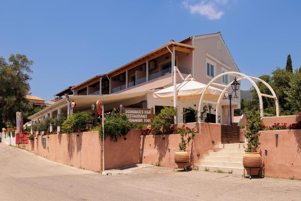 a building with stairs and potted plants on a street at Dominoes Corfu in Ipsos
