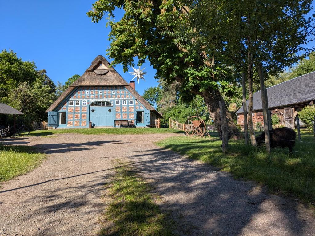 a barn with a blue door and a windmill at Ferienwohnung - De Deelstuuv in Worpswede
