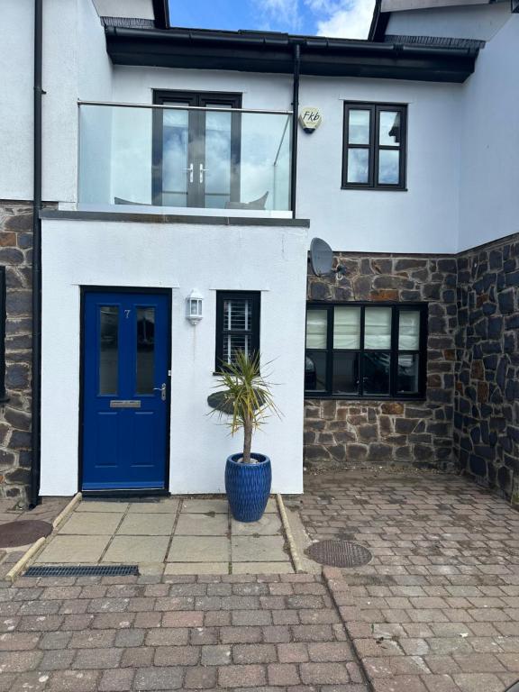 a house with a blue door and a potted plant at Waters Reach in Abersoch