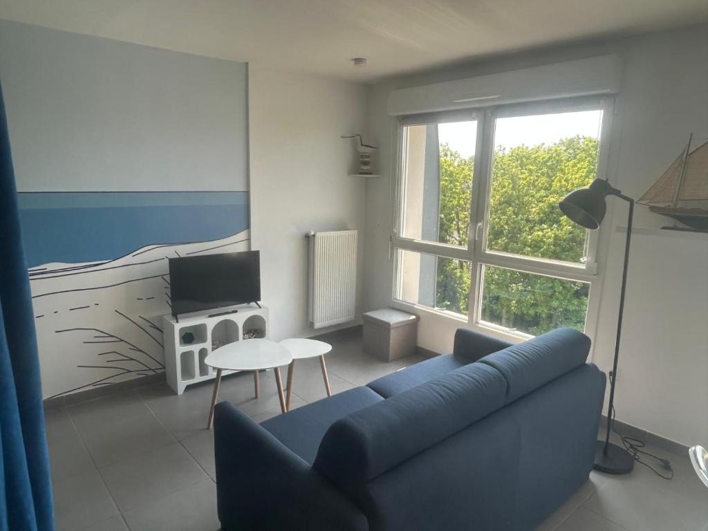 a living room with a blue couch and a bed at Charmant studio vue dégagée à 300m de la plage in Dunkerque