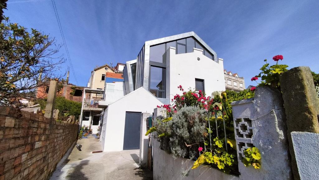a white house with some flowers on a fence at Apartamento Centola julio y agost min 7N in Cangas de Morrazo