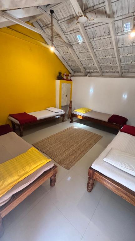 a room with three beds and a yellow wall at Arabica Homestay in Somvārpet