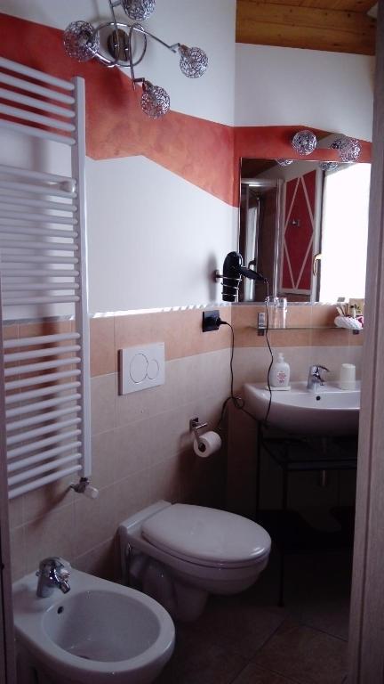 bagno con servizi igienici, lavandino e specchio di La Casa Del Grillo 2 ad Aosta