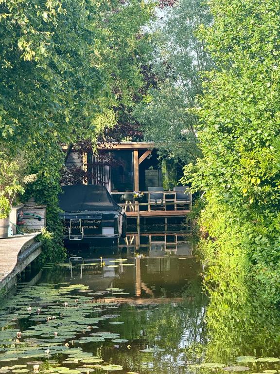 a house on a dock next to a body of water at Casa aan de Plas, B&B met sauna en hottub of jacuzzi in Nieuwkoop
