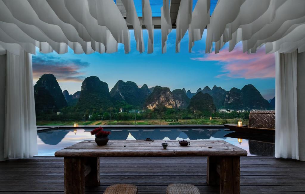 a room with a table and a view of mountains at 自由鸟觅野山舍-阳朔十里画廊遇龙河店 in Yangshuo