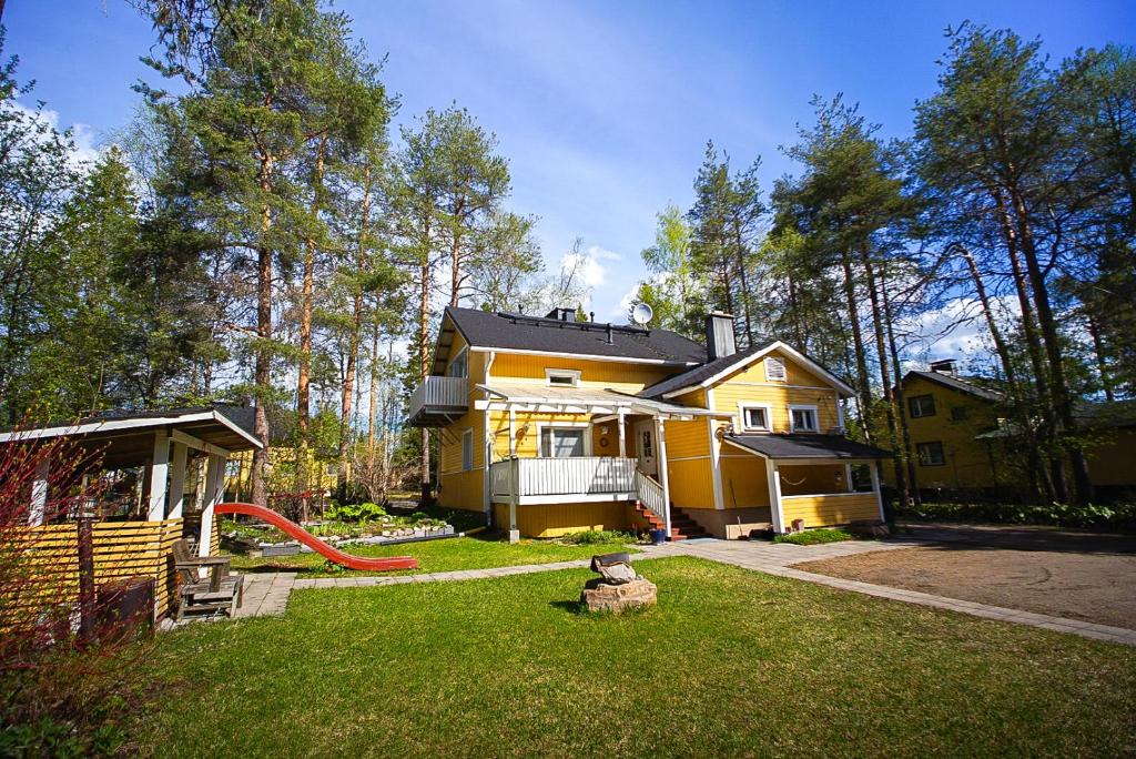 a yellow house with a playground in the yard at Villa Golden Haven in Rovaniemi