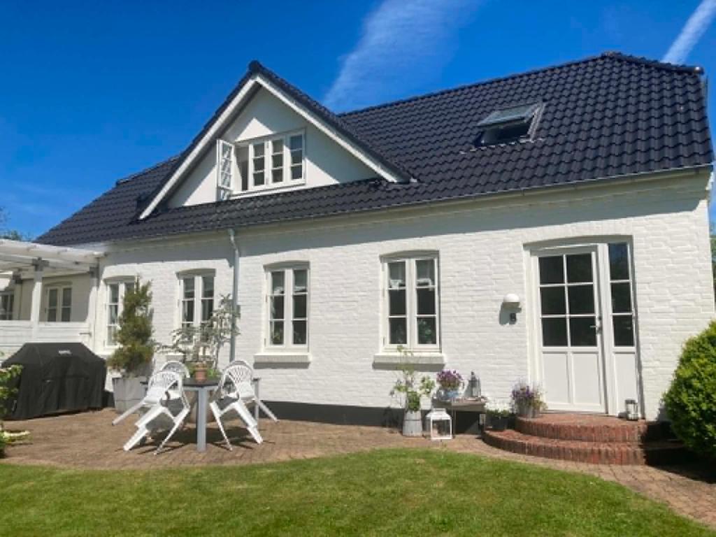 a white house with a black roof at Private country side apartment in Holstebro