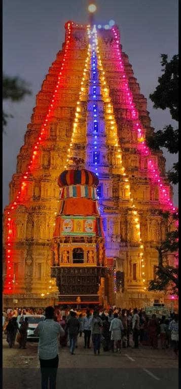 a group of people standing around a large building with lights at Hampi Banana Farm House in Hospet