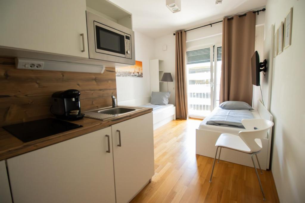 a kitchen with white cabinets and a sink and a bed at MyRoom - Top Munich Serviced Apartments in Munich