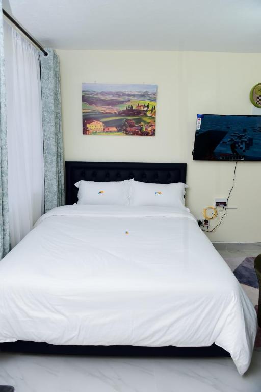 a bedroom with a large white bed with white sheets at comfystdngong in Nairobi