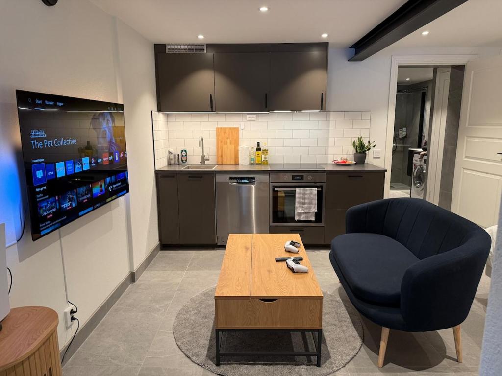 a living room with a blue chair and a table at Cozy Modern Basement in Rättvik in Rättvik