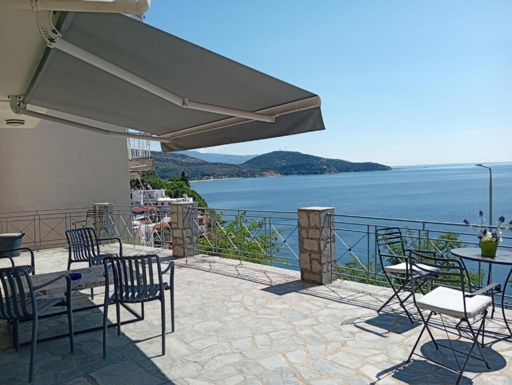 a patio with chairs and tables and a view of the water at Sunrise Suite in Kavála