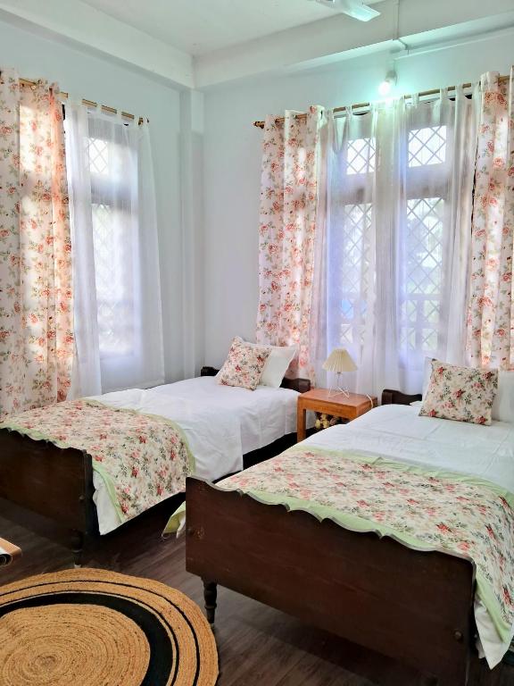 a bedroom with two beds and two windows at sicsac inn in Jorhat