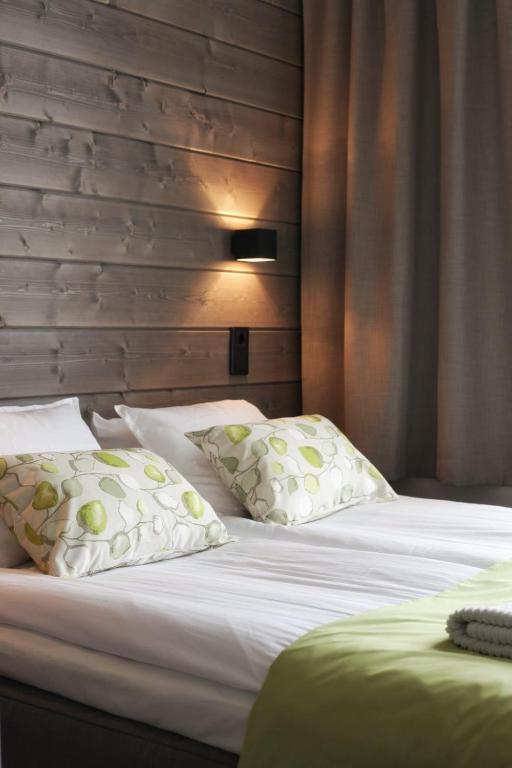 a bedroom with two beds with white sheets and pillows at Hotel Metsähirvas in Rovaniemi