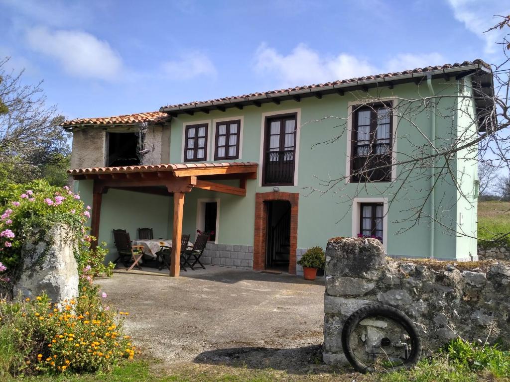 a small green house with a porch at Cuetu del Pradón in Piñeres