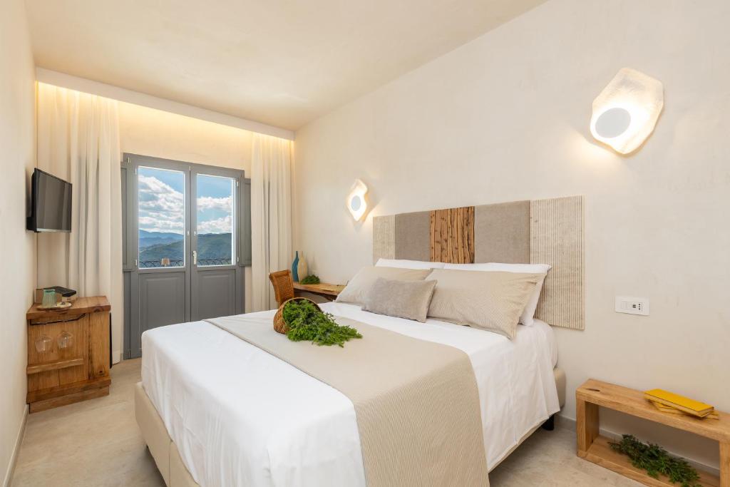 a bedroom with a large white bed and a window at Marinaio di foresta Bedroom in Baunei