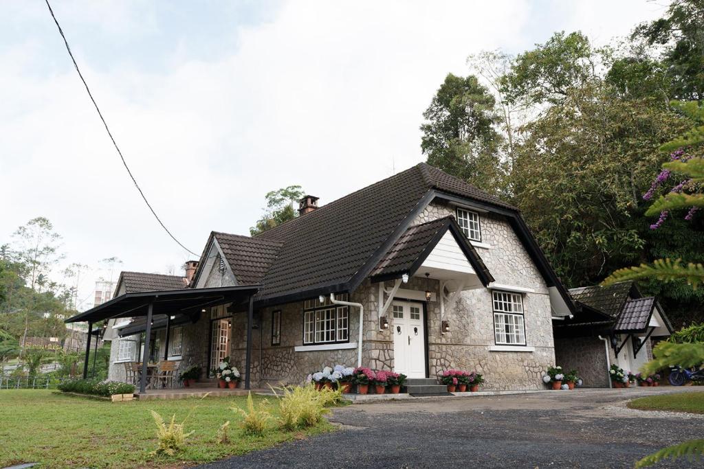 a stone house with a black roof at Rasah Golfers Cottage in Tanah Rata