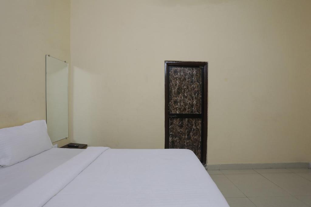 a white bed in a white room with a mirror at Hotel O Celebrity in Chandrapur