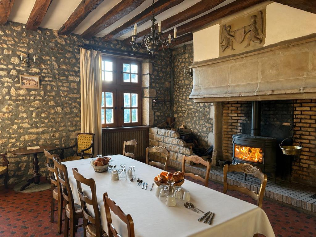 a dining room with a table and a fireplace at Chambre d'hôtes - demeure historique in Chantenay-Saint-Imbert