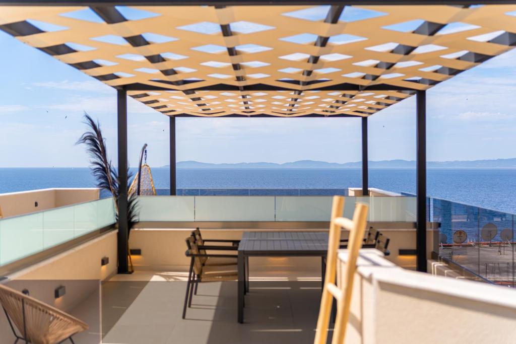 a balcony with a table and chairs and the ocean at SithoniaRS Boho Edition Luxury Roofgarden II in Neos Marmaras