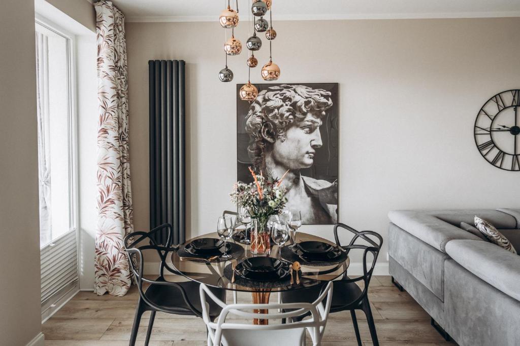 a dining room with a table and a portrait of a man at Apartament Złote Noce in Augustów