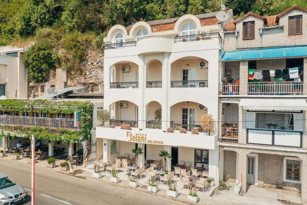 an apartment building with tables and chairs on a street at Apartments Belani Zelenika in Španjola