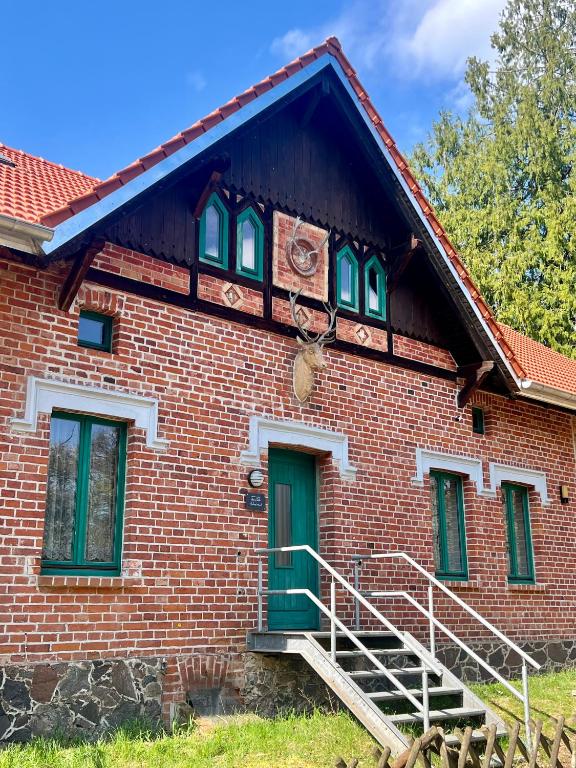 an old brick house with green doors and stairs at Försterei Kalkhorst Ferienhaus am Naturschutzgebiet mit großem Garten in Neustrelitz