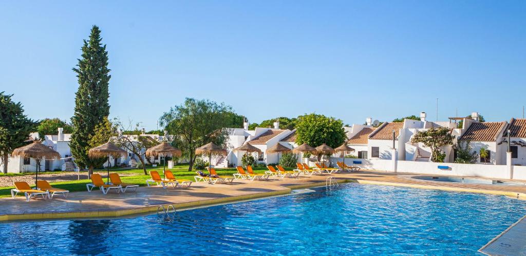 a pool with chairs and umbrellas in a resort at Pedras Da Rainha in Cabanas de Tavira