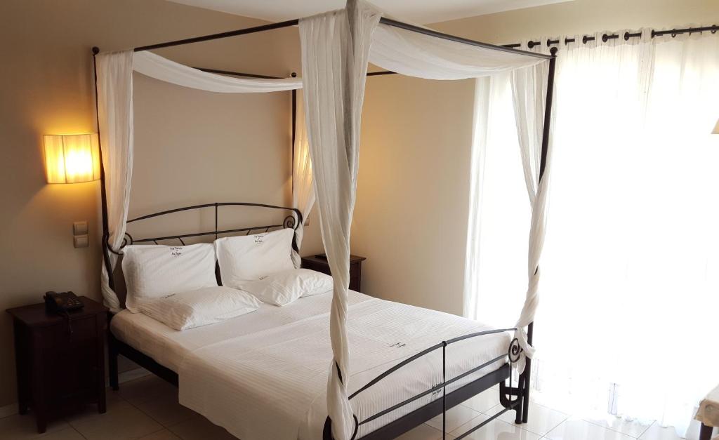 um quarto com uma cama de dossel e uma janela em Sea Sight Boutique Hotel em Porto Rafti