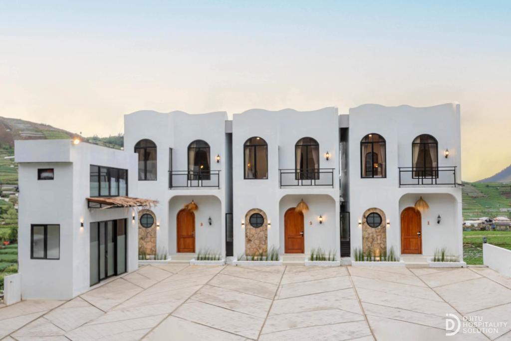 a white house with brown doors and a courtyard at Diamond Cabin 3 in Diyeng