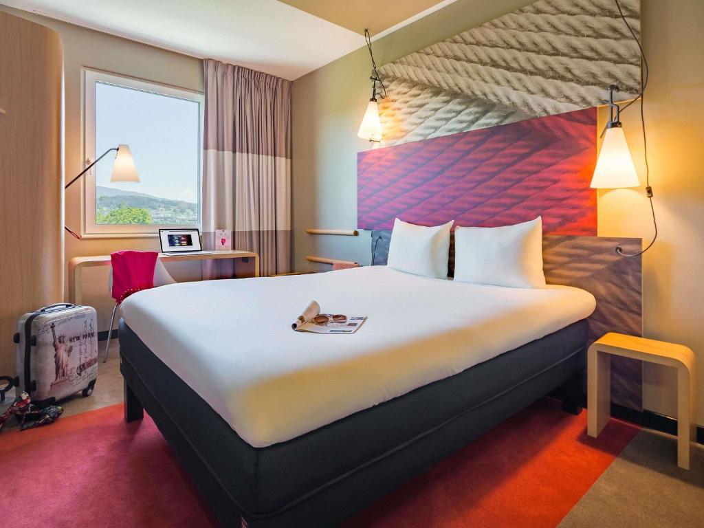a hotel room with a large bed and a window at ibis Baden Neuenhof in Baden