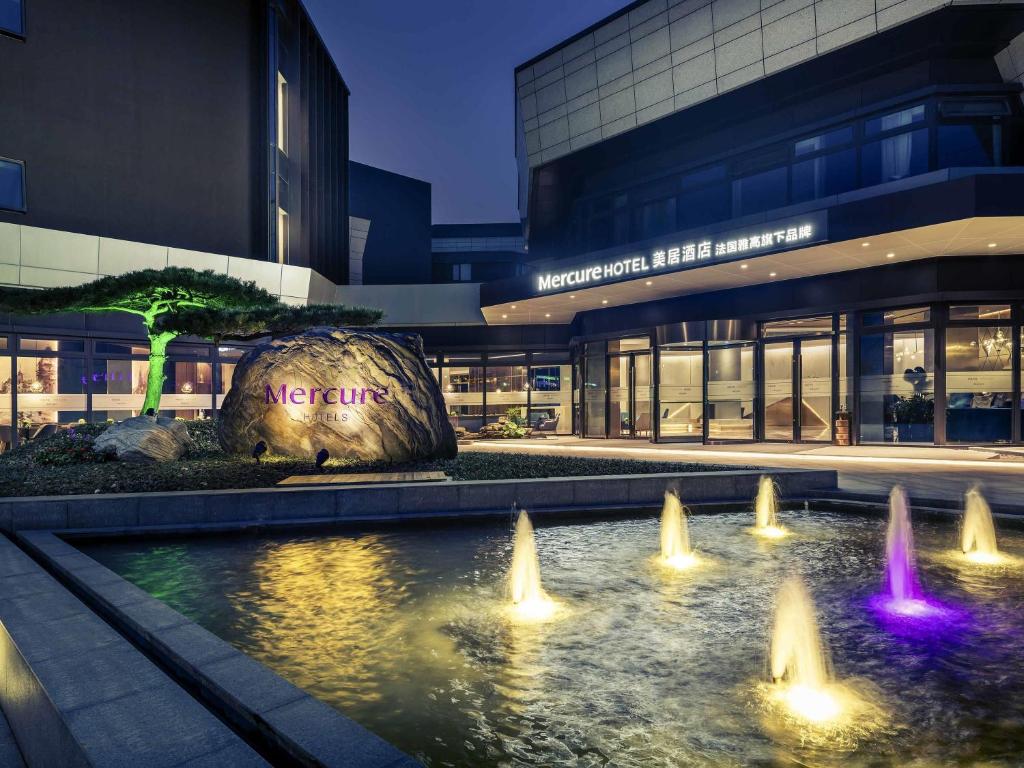 a building with a water fountain in front of a building at Mercure Shanghai NECC in Shanghai