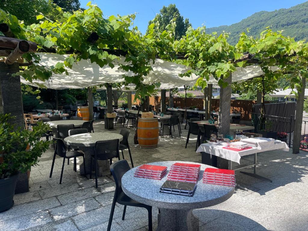 a patio with tables and chairs and a bunch of trees at Hotel Ristorante Grotto Serta in Lamone