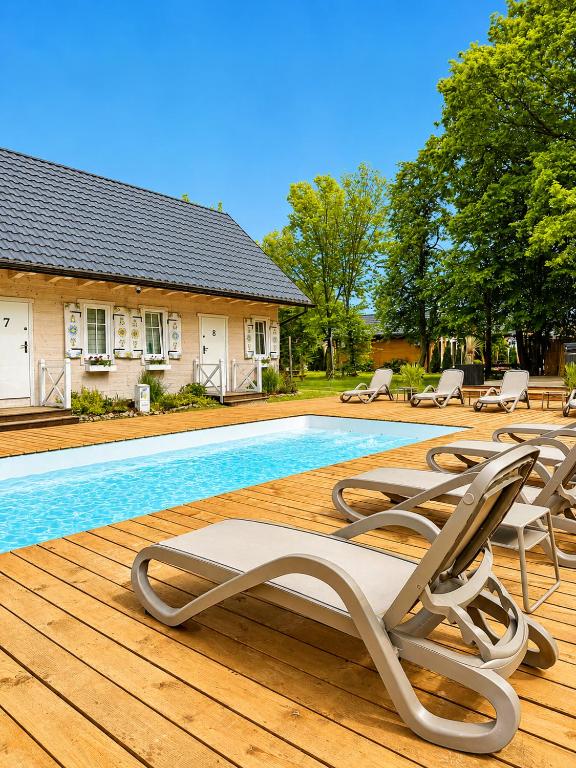 a swimming pool with lounge chairs and a house at Osada Zator Family Resort & SPA in Zator