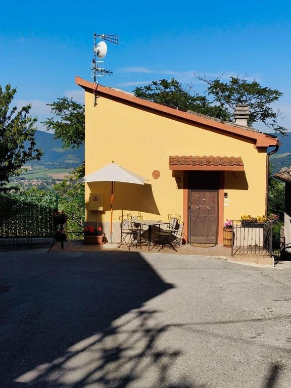 a yellow building with a table and an umbrella at Casa Broglia in Castel Santa Maria