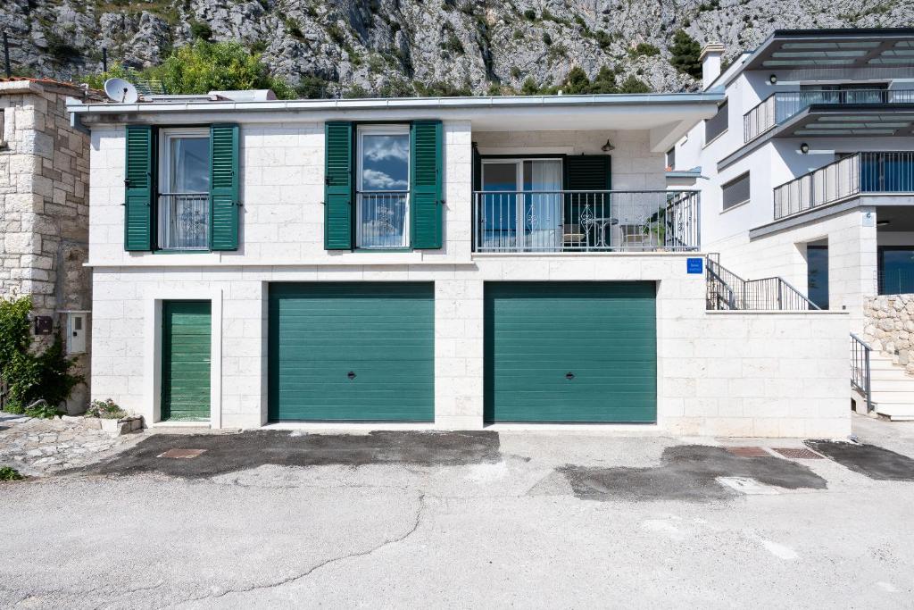 a house with green garage doors in front of a mountain at House Dunja in Omiš