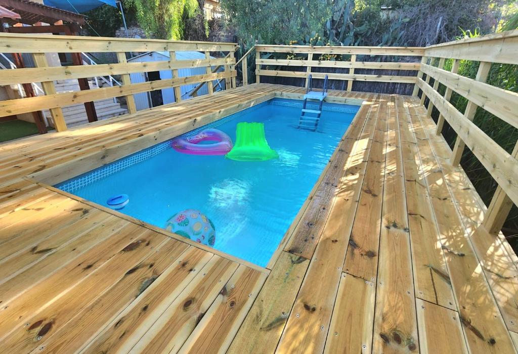 a swimming pool with a wooden deck and a swimming poolvisor at וילה נחל טביה in Arad