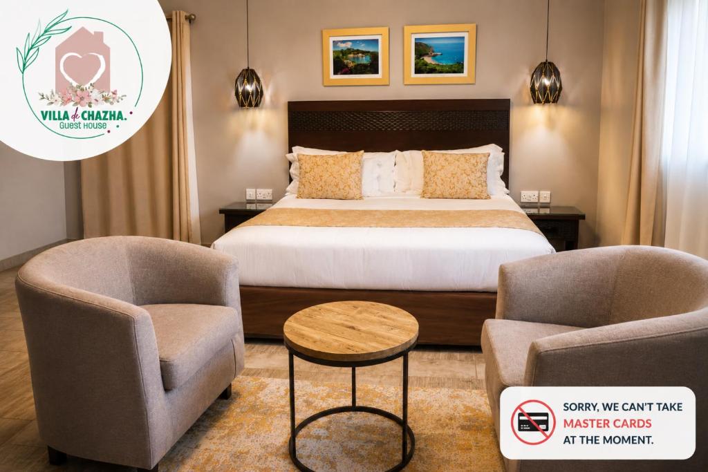 a hotel room with a bed and two chairs at Villa de Chazha Guesthouse in Francistown