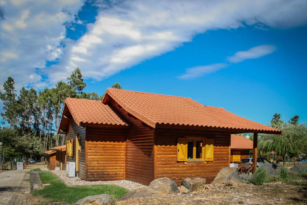 uma pequena cabana de madeira com cortinas amarelas na janela em Camping Oleiros em Oleiros