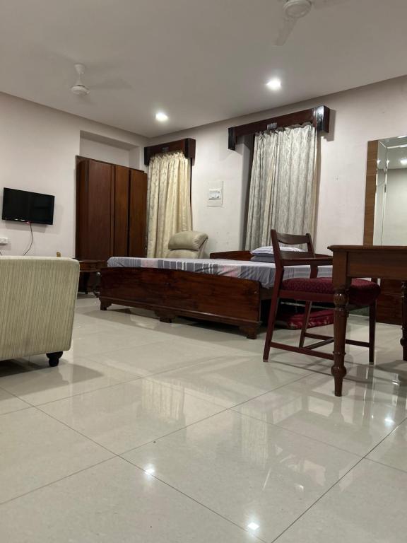 a bedroom with a bed and a couch and a television at AAC in Chennai