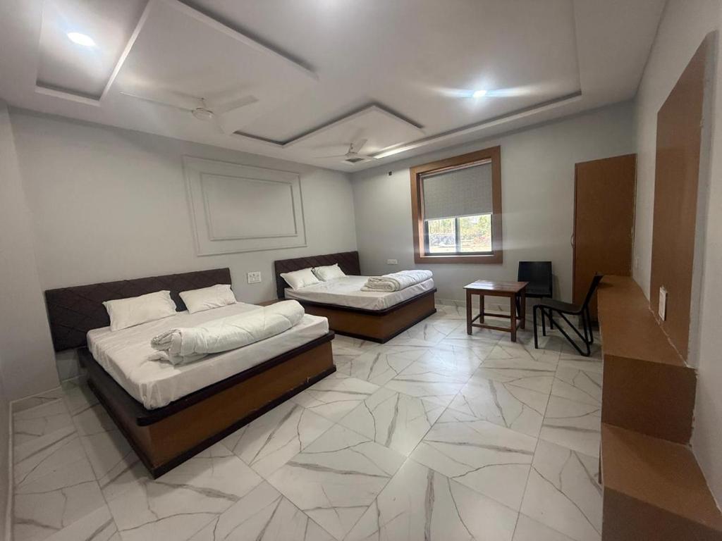 a room with two beds and a table in it at Seasons Resorts in Jabalpur