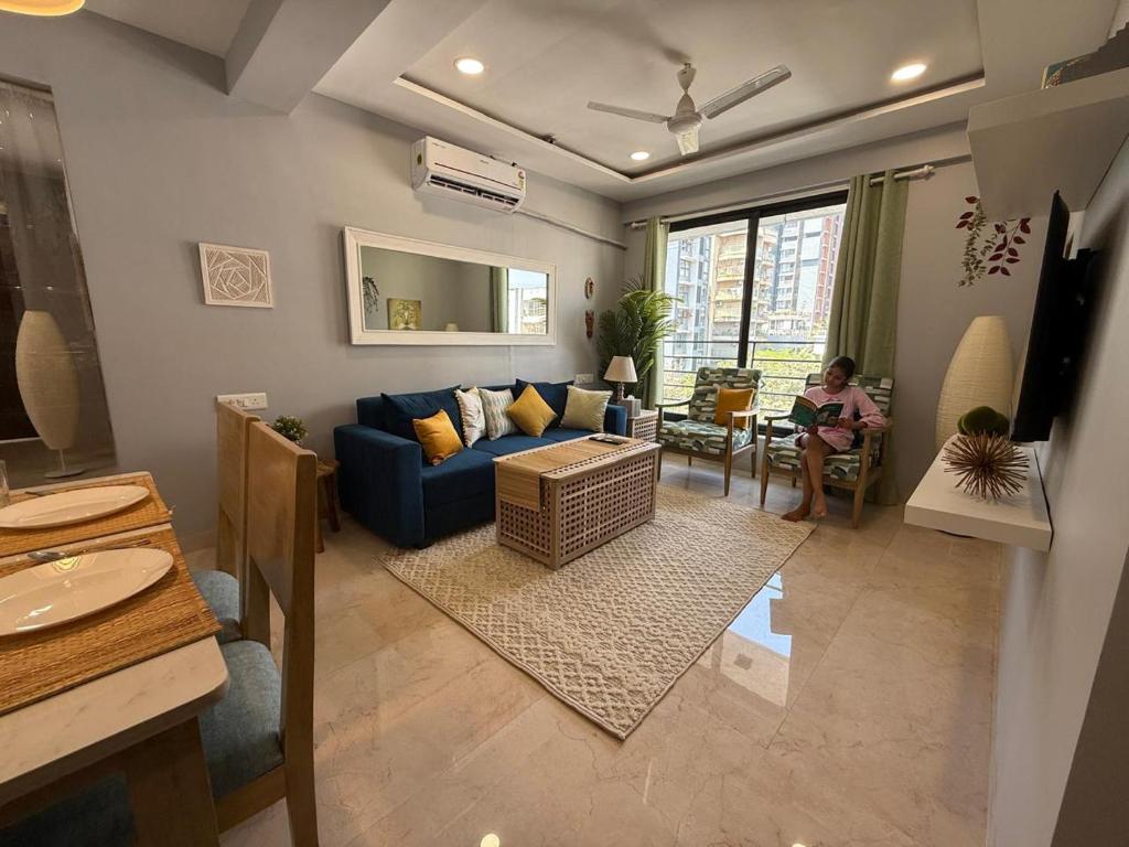 a living room with a blue couch and a person sitting in a chair at Fortune 603 in Mumbai