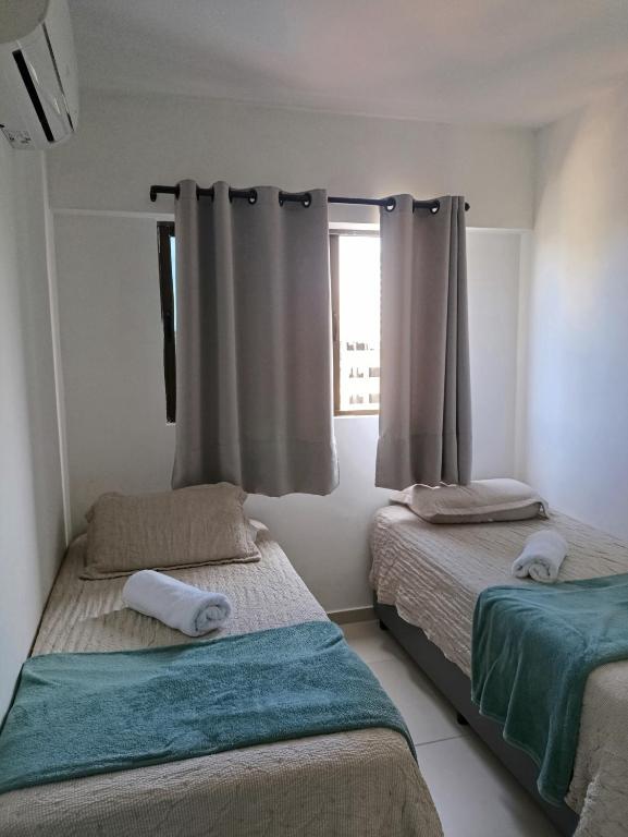 a bedroom with two beds and a window with curtains at Alugo QUARTO em Apartamento -Centro de Recife in Recife