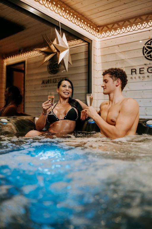 a man and a woman sitting in a hot tub at Willa Regina II Resort & SPA in Zakopane
