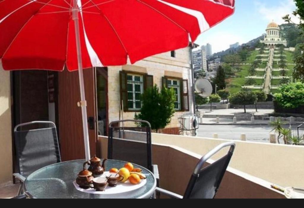 a table with a red umbrella and a plate of food at Haifa Guest House in Haifa